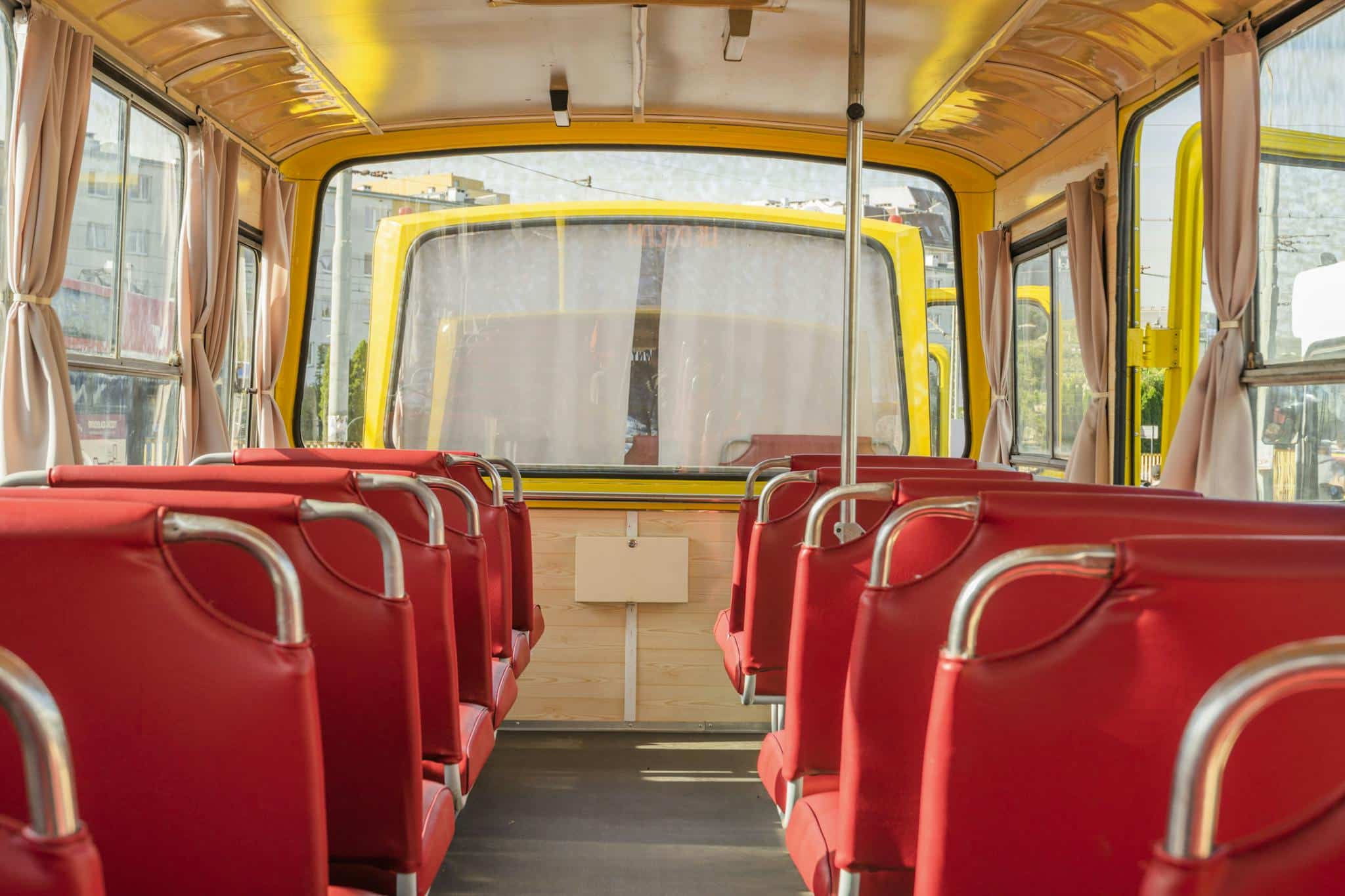 Explore the cozy interior of a yellow bus with vibrant red seats, parked in Wrocław, Poland.