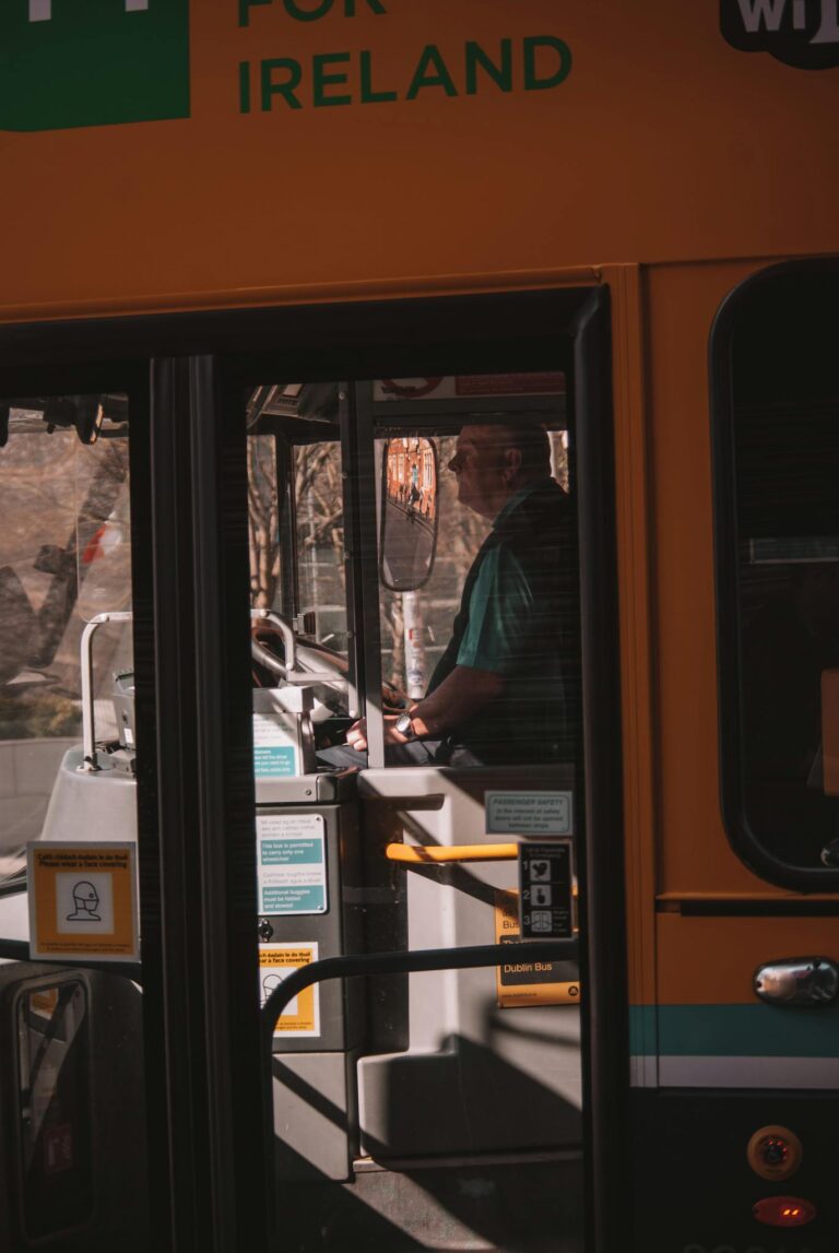 A bus driver focuses on the road while navigating city streets in a public transportation bus.