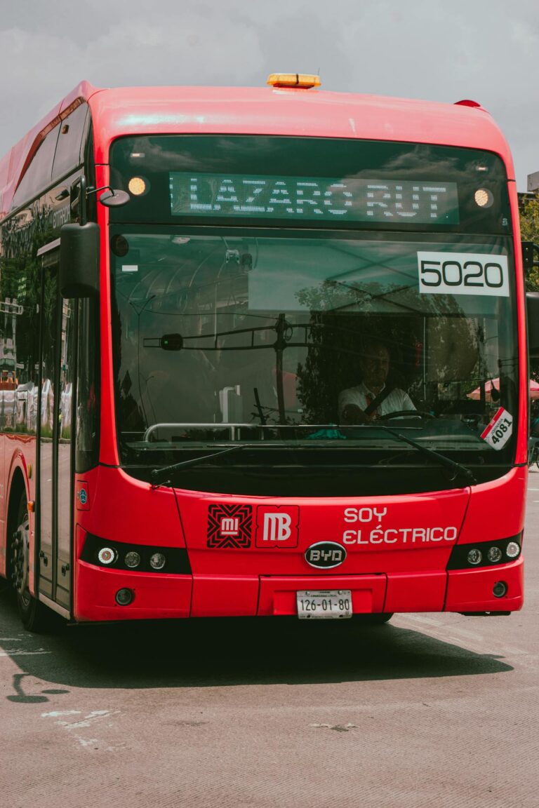 A vibrant red electric bus on a city street, showcasing sustainable urban transport.