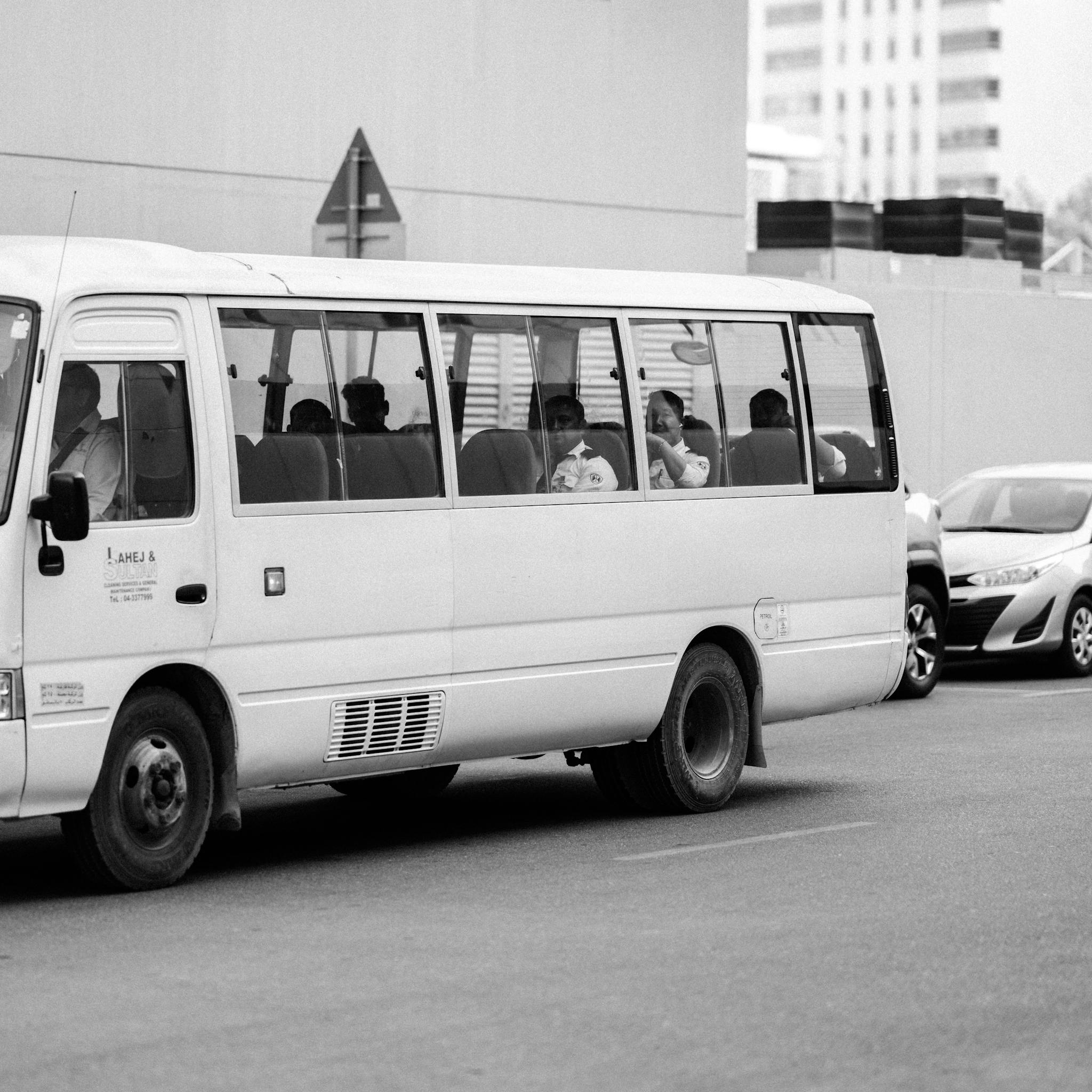 Monochrome image of a bus navigating city streets with passengers inside.